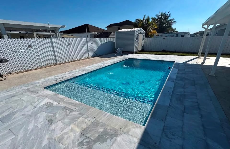 Rectangular modern pool with expansive tanning shelf and silver travertine pavers